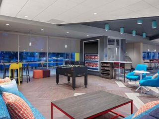 A vibrant recreational room with foosball and pool tables, brightly colored chairs, and a comfortable seating area.